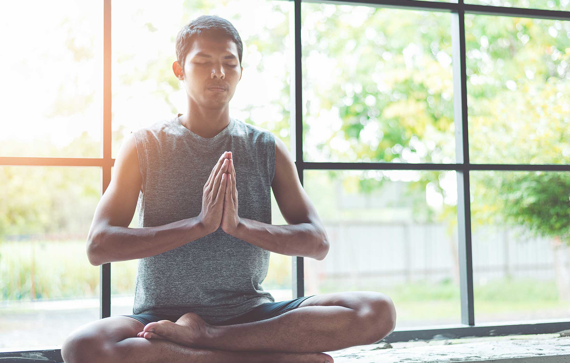 Person in lotus position meditating in front of windows