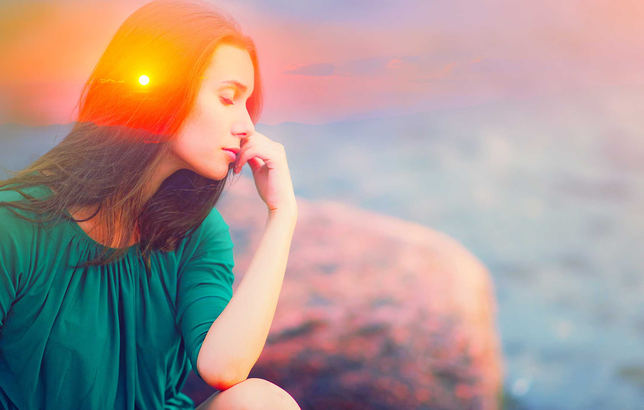 Double exposure picture with silhouette of calm woman overlaid on a scenic sunset with mountains on the horizon