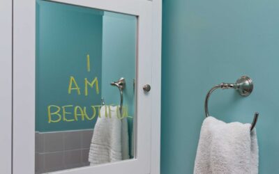 Bathroom mirror with "i am beautiful" written in yellow on it