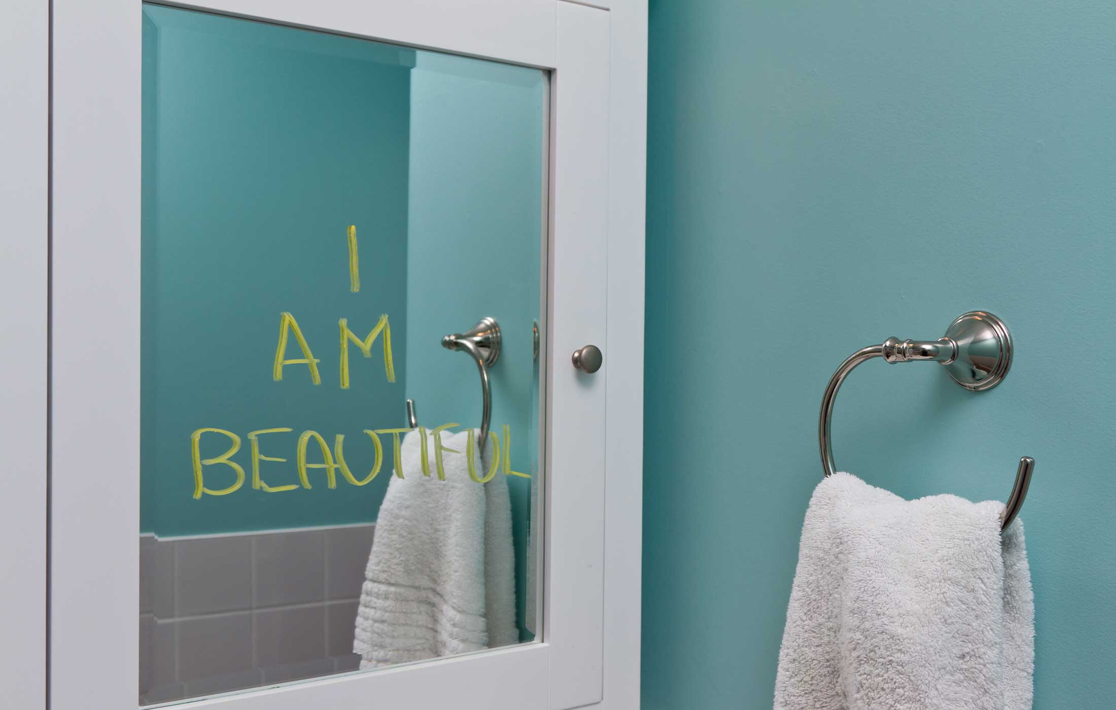 Bathroom mirror with "I AM BEAUTIFUL" written in yellow on it